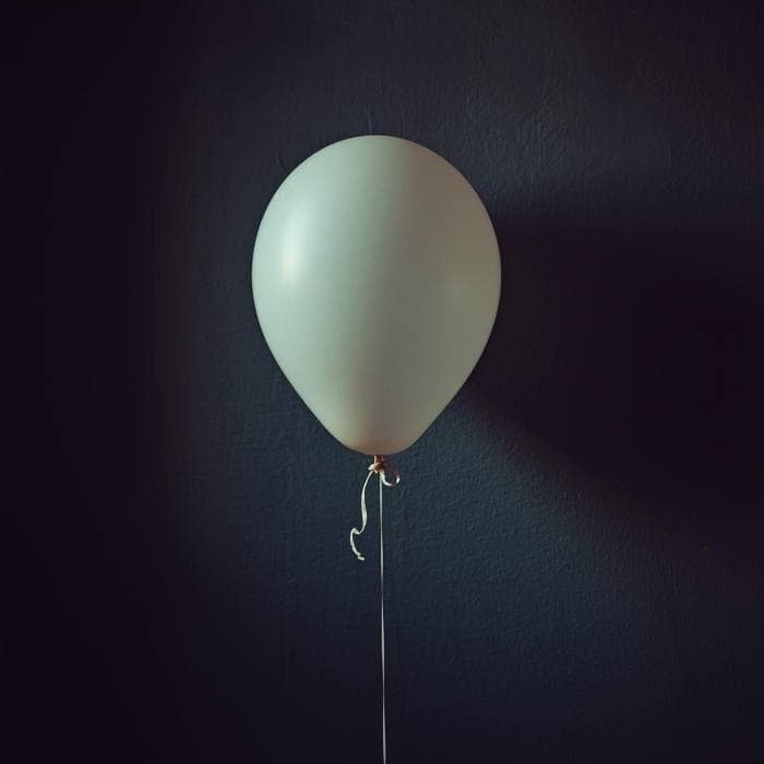 Single matte latex balloon on a dark wall