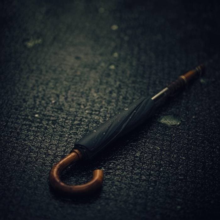 Closed vintage umbrella on wet pavement